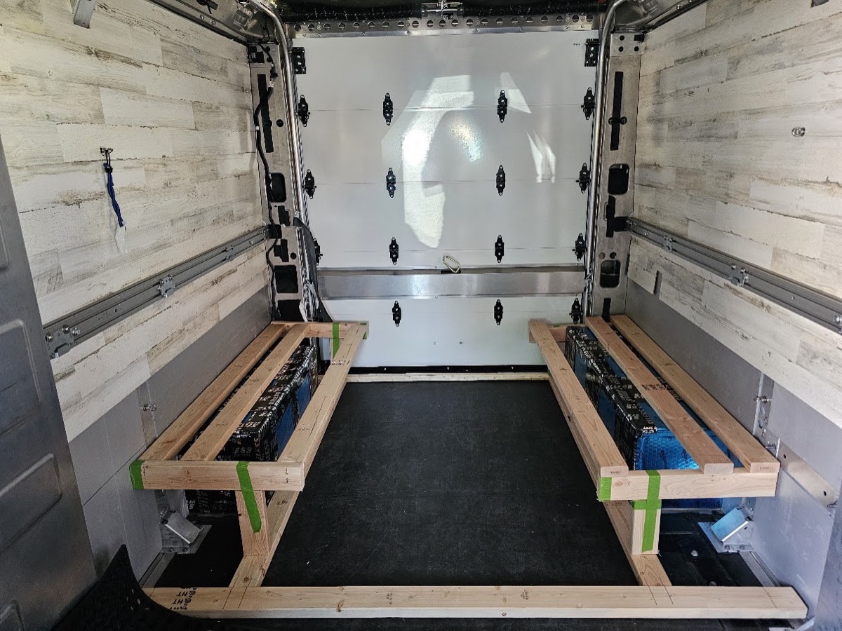 Wood battens taped to the van floor marking a seating layout