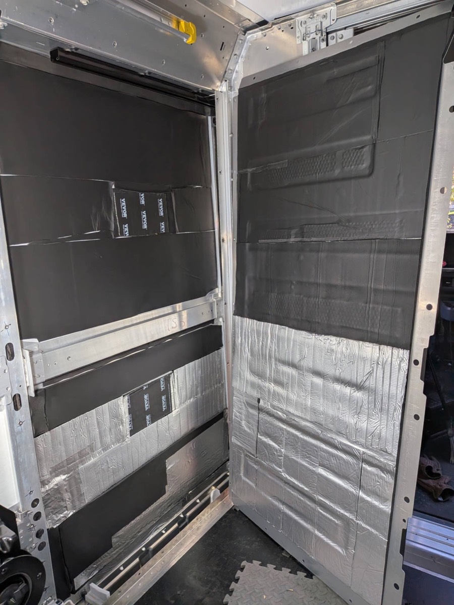 Rigid foam board cut and foil-taped into van wall bays and rear doors