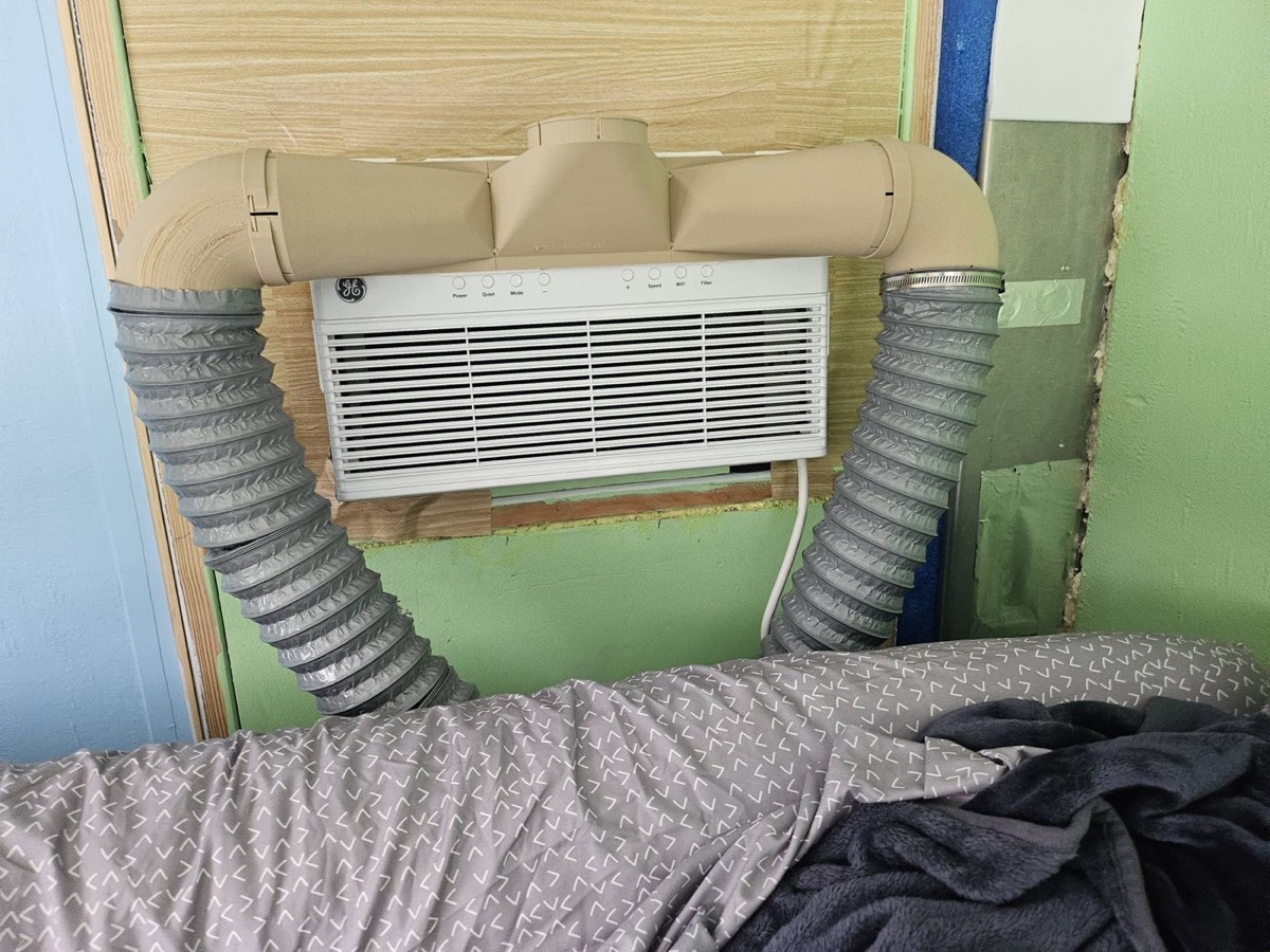 Window heat pump mounted through an interior van wall with flexible ducting